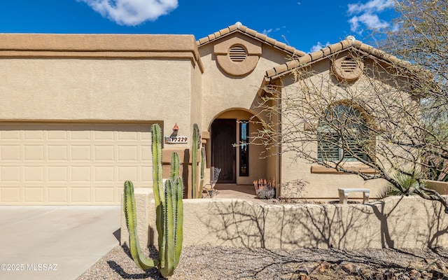 view of front facade with stucco siding, an attached garage, and driveway