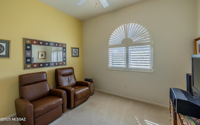 living area with baseboards, ceiling fan, and carpet flooring