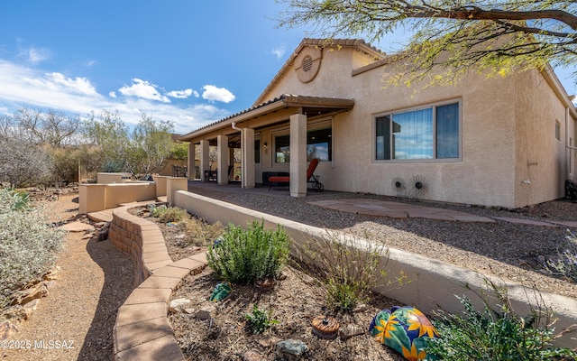 rear view of house with stucco siding and a patio