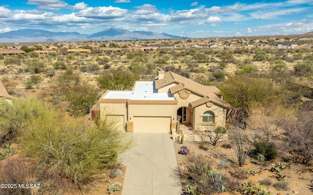 view of front of house featuring stucco siding, a mountain view, concrete driveway, and an attached garage