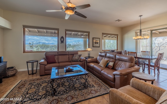 living area with tile patterned floors, visible vents, ceiling fan with notable chandelier, and baseboards