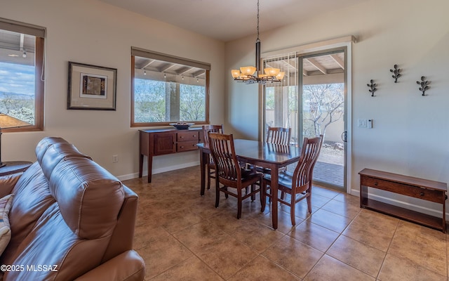 tiled dining space featuring baseboards, plenty of natural light, and an inviting chandelier