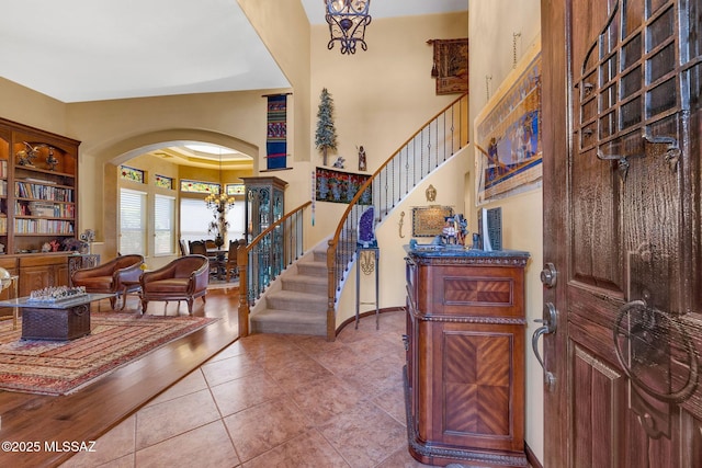 foyer entrance with tile patterned flooring, stairway, baseboards, and arched walkways