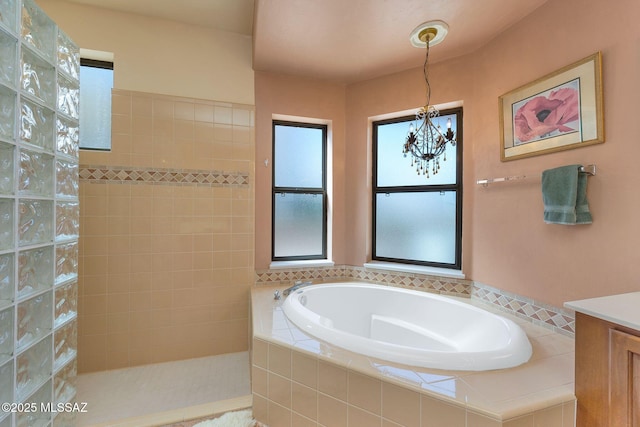 bathroom with a garden tub, a notable chandelier, and a walk in shower