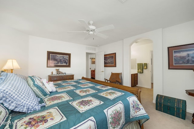 bedroom featuring visible vents, connected bathroom, carpet flooring, arched walkways, and a ceiling fan