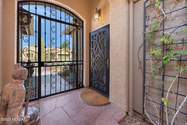 doorway to property with stucco siding and a gate