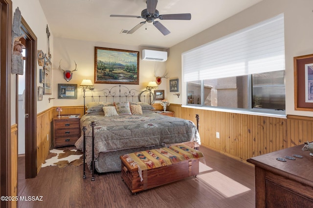 bedroom with a wainscoted wall, visible vents, a wall mounted AC, wood finished floors, and wooden walls