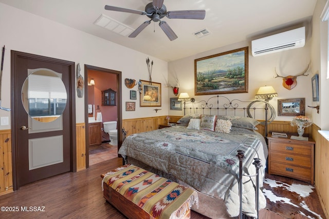 bedroom featuring wood finished floors, visible vents, a wainscoted wall, an AC wall unit, and wood walls