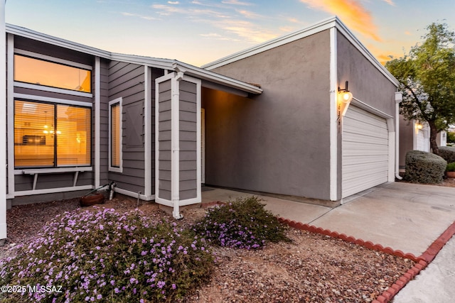 view of home's exterior featuring an attached garage, concrete driveway, and stucco siding