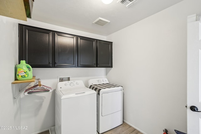 clothes washing area with light wood-type flooring, visible vents, cabinet space, and washing machine and clothes dryer