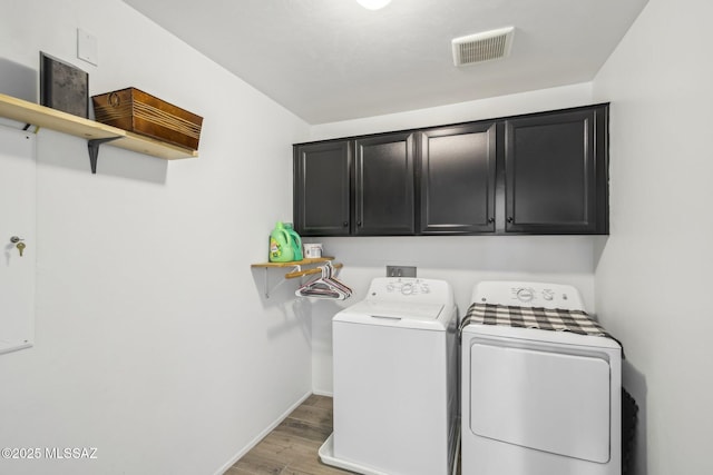 laundry area with light wood finished floors, visible vents, baseboards, washing machine and dryer, and cabinet space