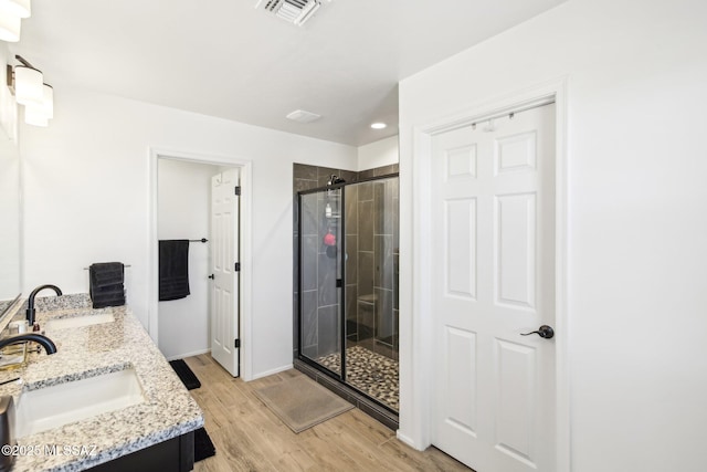 full bath with a sink, visible vents, wood finished floors, and a shower stall