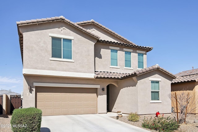 mediterranean / spanish home with a garage, a tile roof, fence, concrete driveway, and stucco siding