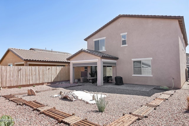 back of house with a tiled roof, stucco siding, a patio, and fence