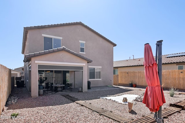 rear view of house featuring a tiled roof, a patio area, a fenced backyard, and stucco siding