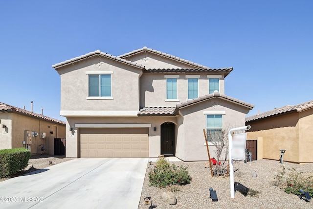 mediterranean / spanish-style house with a tiled roof, stucco siding, an attached garage, and concrete driveway