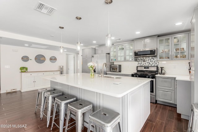 kitchen with tasteful backsplash, visible vents, appliances with stainless steel finishes, wood finish floors, and a sink