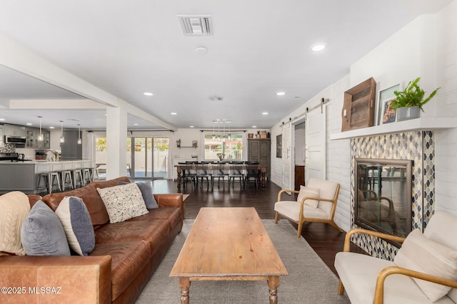 living area featuring a barn door, dark wood-style flooring, visible vents, and recessed lighting