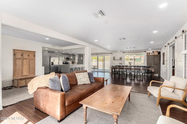 living room with a barn door, wood finished floors, visible vents, and recessed lighting