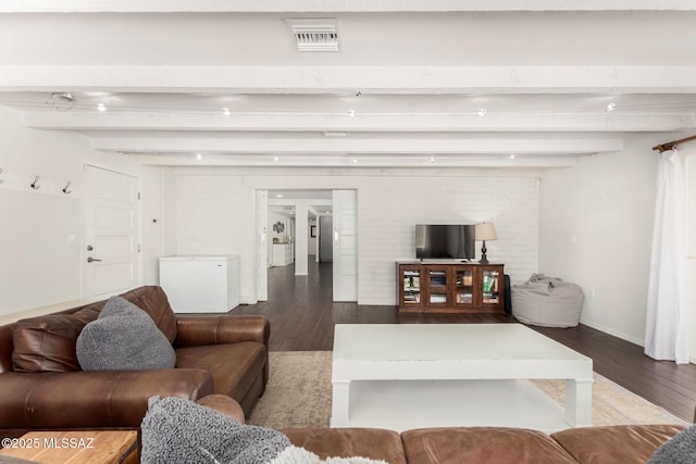 living area with beamed ceiling, wood finished floors, visible vents, and baseboards