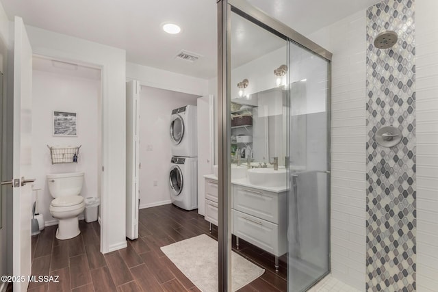 full bath with visible vents, wood tiled floor, a shower stall, stacked washing maching and dryer, and vanity