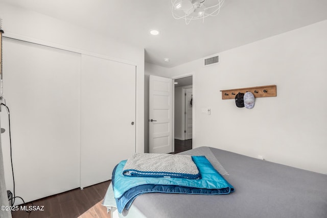 bedroom with a closet, wood finished floors, and visible vents