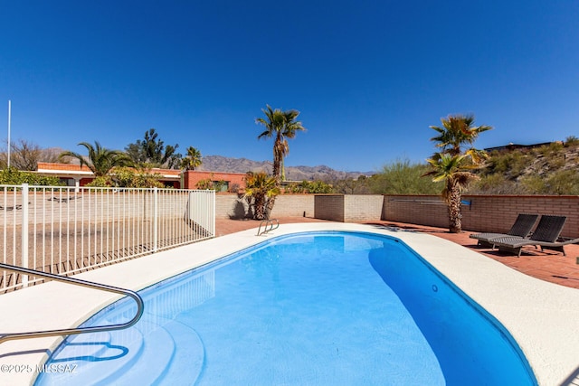 view of pool with a patio area, a fenced backyard, a mountain view, and a fenced in pool