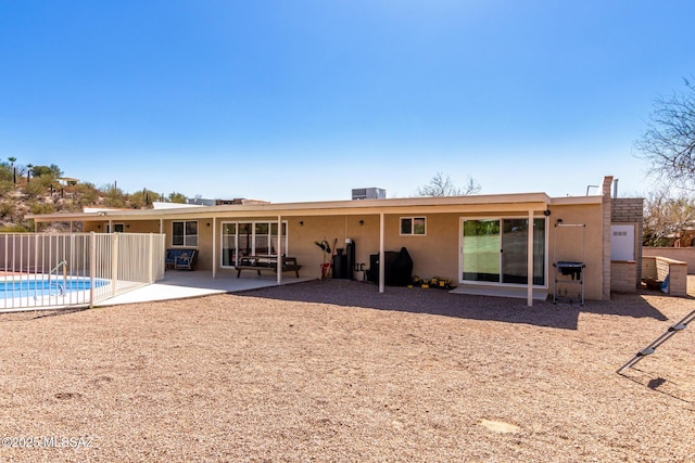 rear view of property featuring a patio, central AC unit, fence, a fenced in pool, and stucco siding