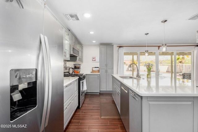 kitchen with stainless steel appliances, plenty of natural light, a sink, and gray cabinetry