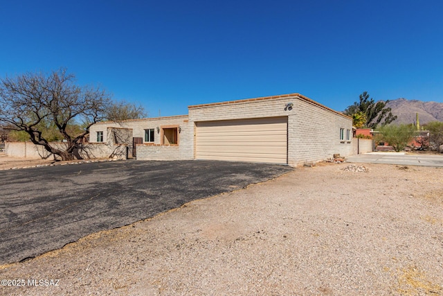 ranch-style house featuring driveway, an attached garage, a mountain view, and brick siding