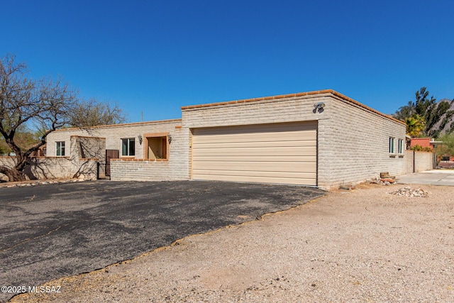 view of front facade featuring driveway, brick siding, and an attached garage