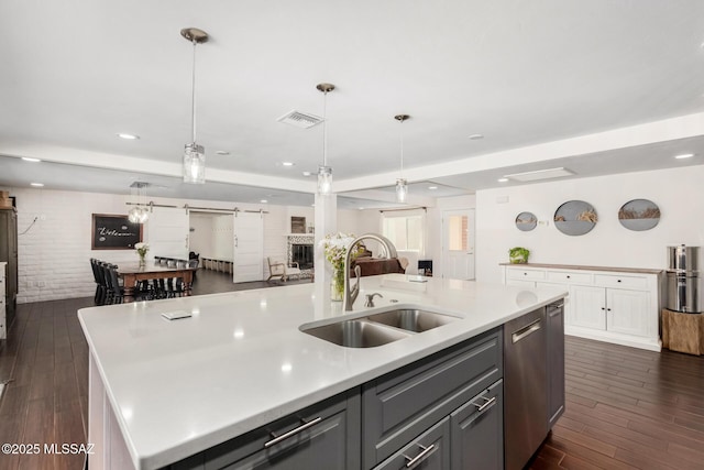 kitchen featuring visible vents, a barn door, open floor plan, a sink, and dishwasher