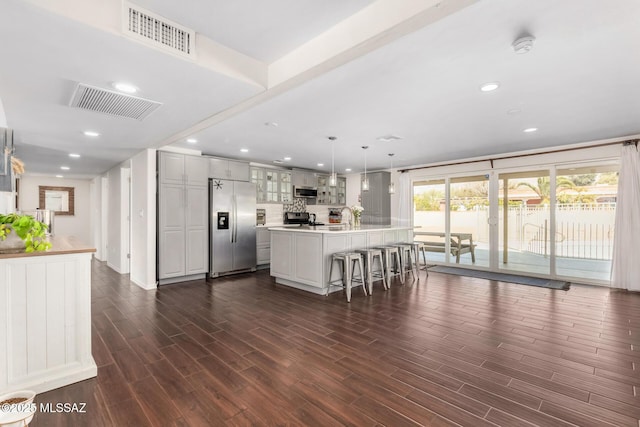 kitchen featuring appliances with stainless steel finishes, dark wood-style flooring, visible vents, and glass insert cabinets