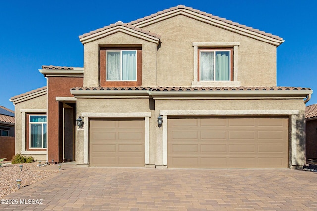 view of front of house featuring a garage, decorative driveway, and stucco siding