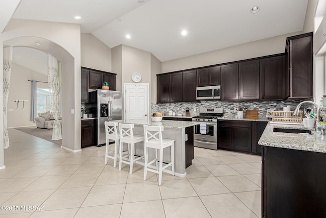 kitchen with a breakfast bar area, appliances with stainless steel finishes, a sink, and light tile patterned flooring