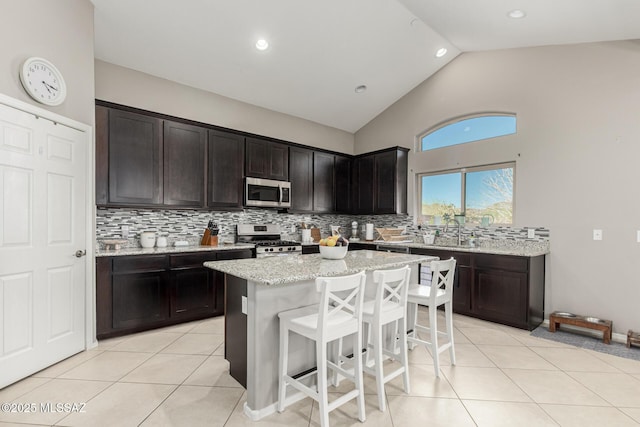 kitchen featuring a breakfast bar, light tile patterned floors, stainless steel appliances, and backsplash