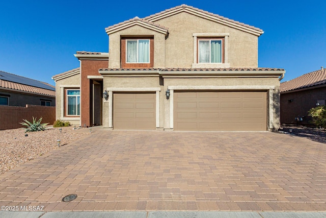 view of front of home featuring a garage, a tiled roof, decorative driveway, and stucco siding