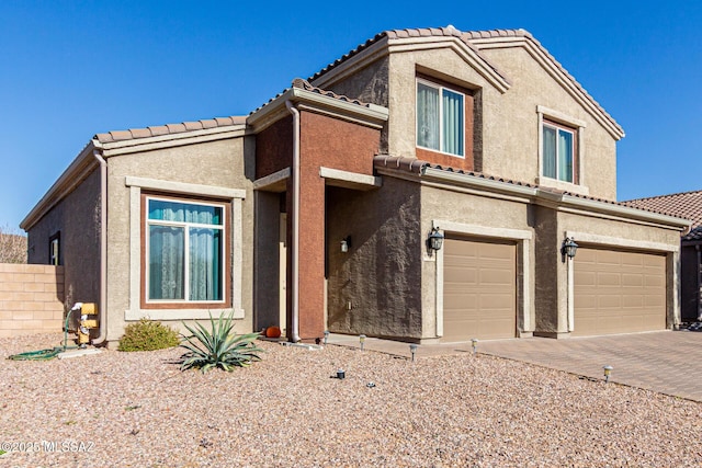 view of front of house with a garage, a tile roof, and stucco siding