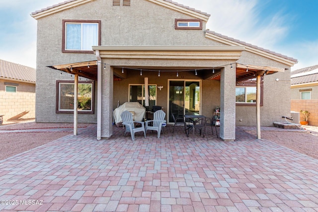 back of house with a patio area, a tile roof, fence, and stucco siding