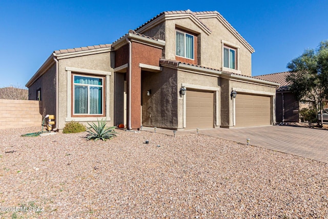 view of front of property with fence, a tiled roof, an attached garage, and stucco siding