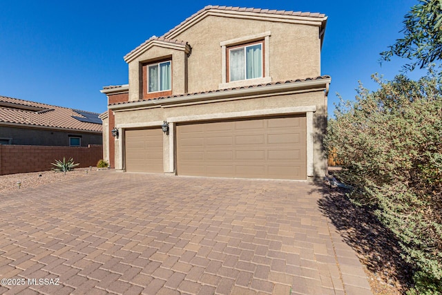 mediterranean / spanish-style house featuring decorative driveway, a tile roof, and stucco siding