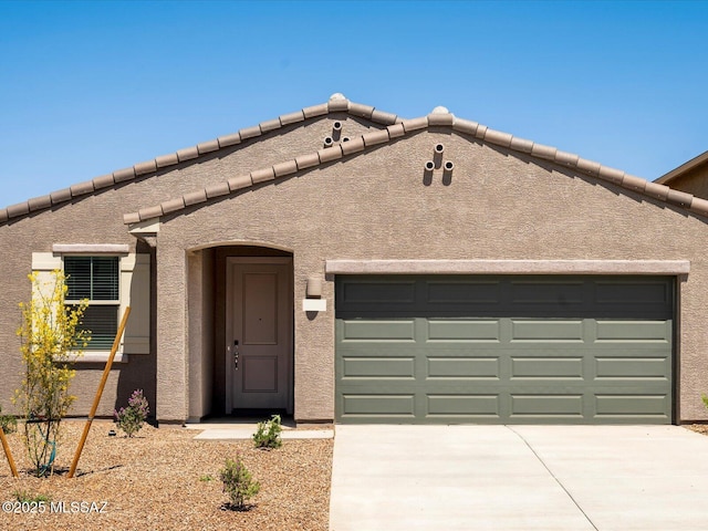 view of front of property featuring driveway, stucco siding, an attached garage, and a tile roof