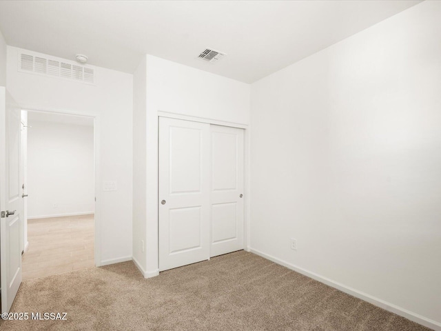 unfurnished bedroom featuring light colored carpet, baseboards, and a closet