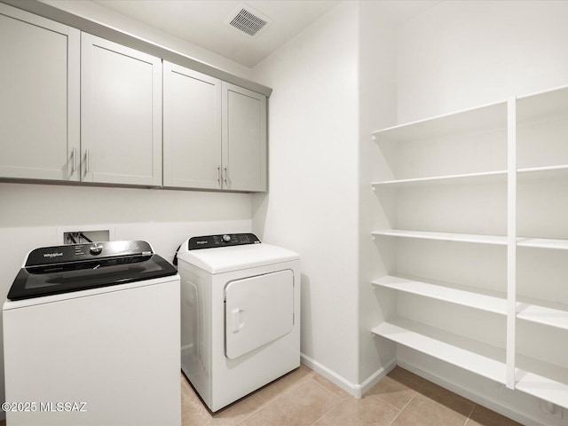laundry area featuring separate washer and dryer, cabinet space, baseboards, and light tile patterned floors