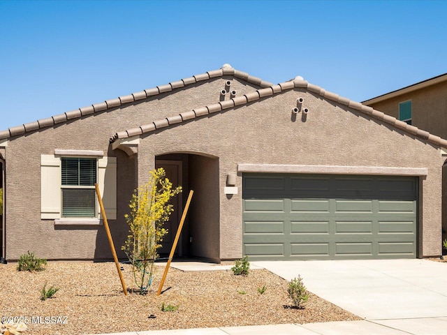 view of front of home with a garage, stucco siding, concrete driveway, and a tiled roof