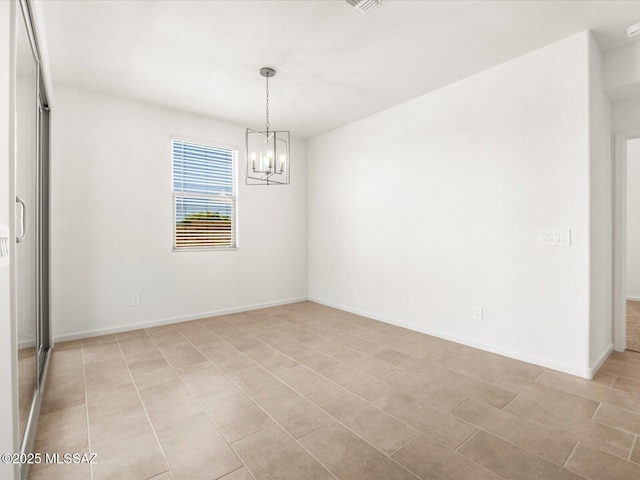 empty room featuring a chandelier and baseboards