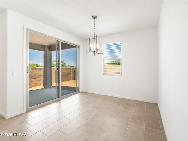 spare room featuring plenty of natural light, a chandelier, and baseboards