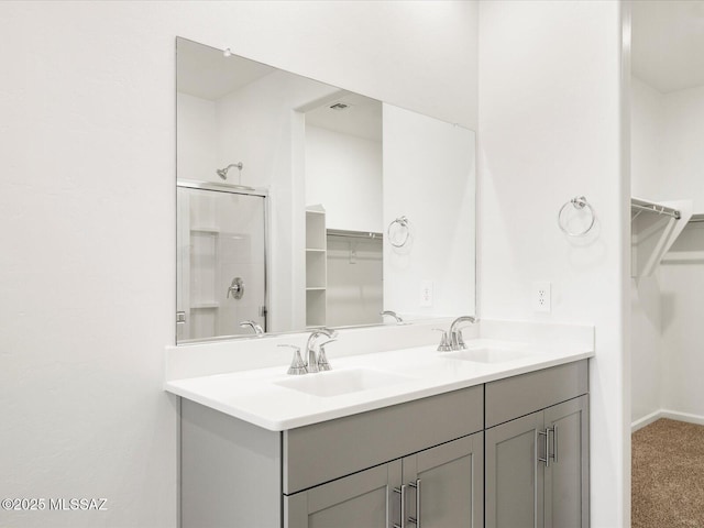 full bath with a spacious closet, an enclosed shower, double vanity, and baseboards