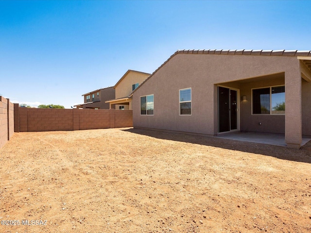 rear view of house with a fenced backyard, a patio, and stucco siding