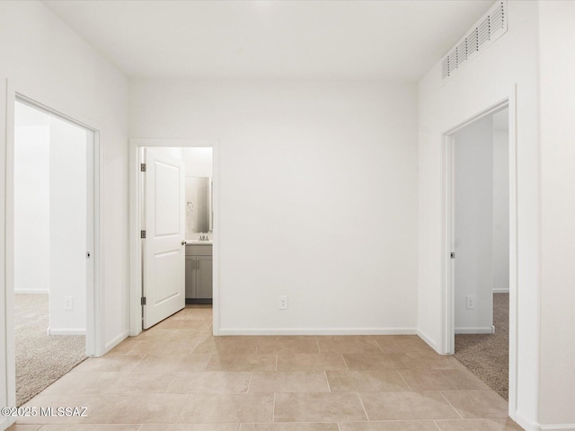 unfurnished bedroom with a spacious closet, baseboards, and connected bathroom